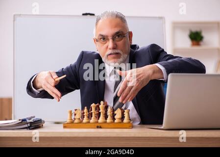 Alter Geschäftsmann Angestellter, der Schach am Arbeitsplatz spielt Stockfoto