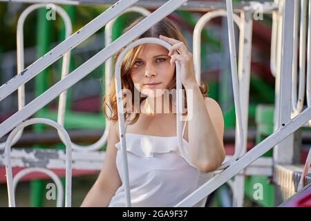 Attraktive seriöse Frau sitzt hinter Zaun im Freien. Stockfoto