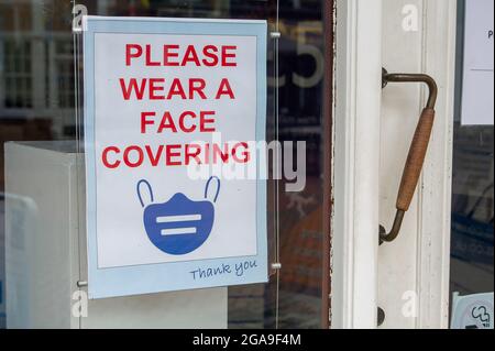 Chesham, Buckinghamshire, Großbritannien. Juli 2021. A Bitte tragen Sie eine Gesichtsbedeckung in einem Schaufenster. Quelle: Maureen McLean/Alamy Stockfoto