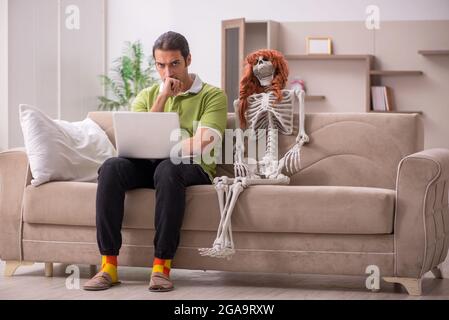 Mann, der auf dem Sofa mit weiblichem Skelett sitzt Stockfoto