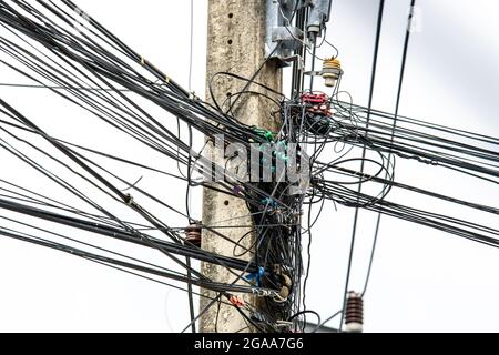 Störung chaotische Linie von schwarzen elektrischen Drähten auf alten Strompol. Komplizierte Anordnung von elektrischen Kabeln mit Himmelshintergrund. Ausgelastes Dienstprogramm Stockfoto