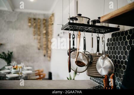 Das Design der modernen Wohnküche im Loft-Stil und rustikal. Schwarze Wand mit Regalen, Tabletts, Gläser, Tassen, Waschbecken Stockfoto