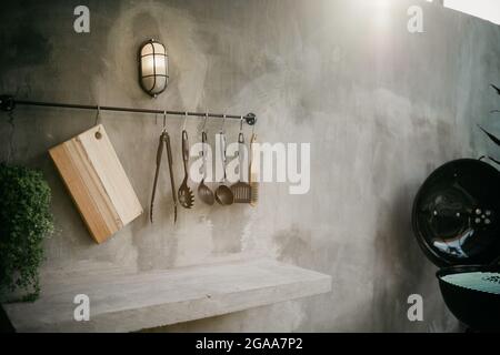 Das Design der modernen Wohnküche im Loft-Stil und rustikal. Schwarze Wand mit Regalen, Tabletts, Gläser, Tassen, Waschbecken Stockfoto