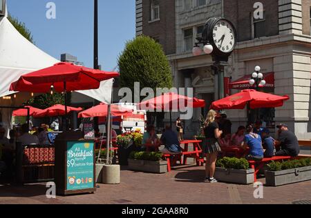 Die Außenterrasse eines Restaurants ist durch rote Sonnenschirme auf der Government Street in Victoria, British Columbia, auf Vancouver Island, vor der Sonne geschützt. Stockfoto