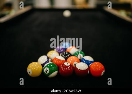 Billard Pool Spiel. Farbige Kugeln in einem Dreieck, die auf eine weiße Kugel gerichtet sind. Dunkler Leinentisch. Billardkugeln auf dem Tisch Stockfoto