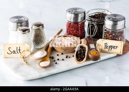 Nahaufnahme eine Auswahl an Salz und Pfeffer in verschiedenen Behältern und Löffeln. Stockfoto