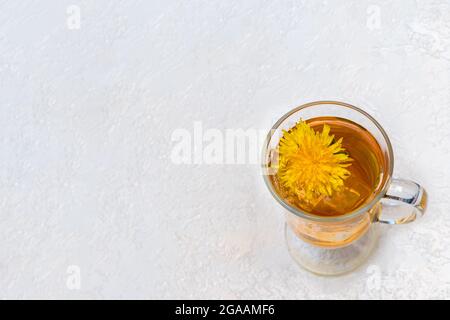 Gesunder Kräutertee mit Delelionen in einer Glasschale, Eis und gelber Dandelionenblume innen auf weißem Hintergrund, Draufsicht, Kopierraum, Nahaufnahme. Summe Stockfoto