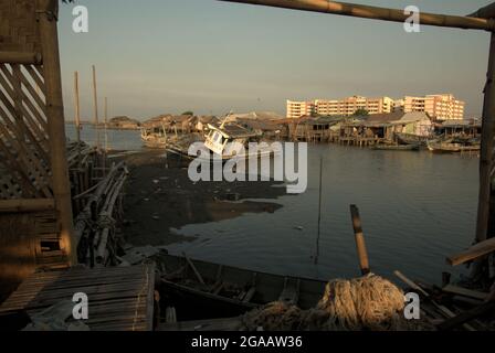 Gezeitenstrand und Stelzenhäuser im Hintergrund neuer flacher Gebäude im Küstendorf Marunda in Cilincing, Jakarta, Indonesien. Stockfoto