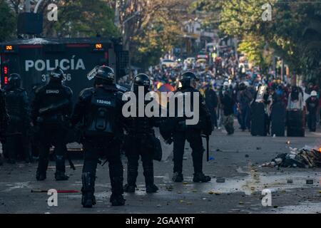 Medellin, Kolumbien. Juli 2021. Die kolumbianischen Polizeibeamten decken sich hinter einem gepanzerten Lastwagen ab, als die Demonstrationen in den späten Abendstunden zu Zusammenstößen zwischen der kolumbianischen Bereitschaftspolizei (ESMAD) und den Demonstranten führten, während Kolumbien 3 Monate lang gegen die Regierung des kolumbianischen Präsidenten Ivan Duque protestiert, Und eine neue Steuerreform inmitten von Unruhen und Gewalt, die seit Beginn der Proteste mindestens 83 Tote hinterlassen haben. Am 28. Juli 2021 in Medellin - Antioquia, Kolumbien. Kredit: Long Visual Press/Alamy Live Nachrichten Stockfoto