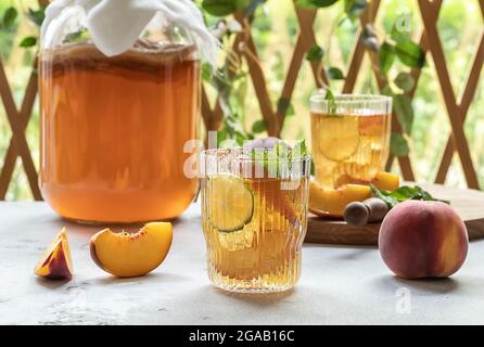 Hausgemachte Gärung. Kombucha-Tee leicht alkoholisches, leicht brausendes Getränk mit Pfirsich und Limette. Stockfoto