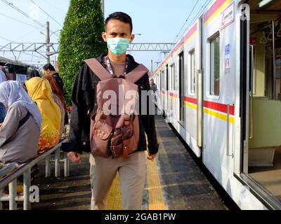 Ein Mann trägt eine Gesichtsmask, während er in einem Bahnhof läuft. Stockfoto