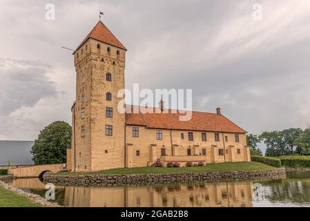 Gelbe Burg mit einem hohen Turm, der sich im Graben widerspiegelt, Tosterup, Schweden, 16. Juli 2021 Stockfoto