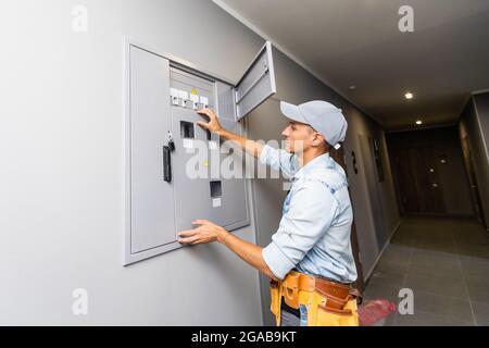 Junger lächelnder Elektriker, der seine Arbeit verrichten wird Stockfoto