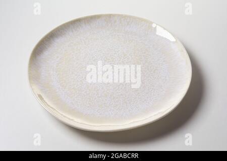 Von oben runde Keramikplatte mit glänzendem Emaille mit Rissen-Effekt auf grauem Hintergrund bedeckt Stockfoto