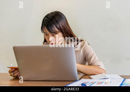 Asiatische Bürofrau, die an Laptop und Dokumenten arbeitet Stockfoto