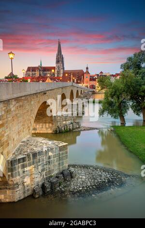 Regensburg, Deutschland. Stadtbild von Regensburg, Deutschland mit der alten Steinbrücke über die Donau und dem Petersdom bei Sonnenaufgang im Sommer. Stockfoto