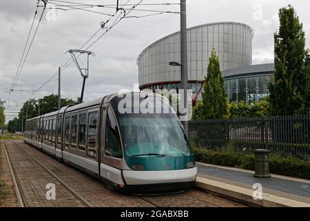 STRASSBURG, FRANKREICH, 24. Juni 2021 : EINE Straßenbahn fährt auf ihrer Schiene vor dem modernen Gebäude des Europäischen Gerichtshofs für Menschenrechte. Stockfoto