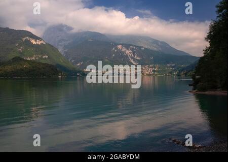 Die Stadt Molveno, unter den oft von Wolken umhüllten Gipfeln der Brenta-Dolomiten, ist die einzige Siedlung jeder Größe am Ufer des ‘schönsten Sees Italiens’, des Lago di Molveno in Trentino-Südtirol, Italien. Die Stadt ist ein beliebtes Sommerziel für Besucher, die von der natürlichen Schönheit des Sees, seinem sauberen alpinen Wasser und Aktivitäten wie Bootfahren, Windsurfen, Angeln und Kanufahren angezogen werden. Stockfoto