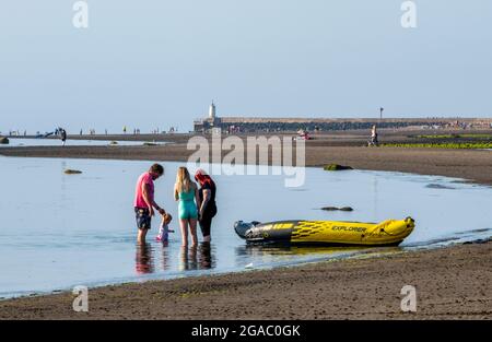 Familie am Meer, Familie am Strand mit aufblasbaren, heißen Sommern Tag am Strand, Familie mit aufblasbarem Kajak am Strand, Familie auf Aufenthalt. Stockfoto