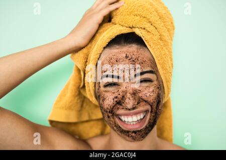 Junge lächelnde Frau Anwendung Kaffee Peeling Maske auf Gesicht - Happy girl mit Hautpflege Spa Tag zu Hause Stockfoto