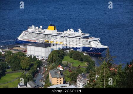 Blick auf ein Kreuzschiff mit dunkelblauem Rumpf und gelbem Trichter, das vom Gipfel der Standseilbahn Floibanen und dem Mount Fløyen, Bergen, Norwegen, im Hafen angedockt ist. Stockfoto