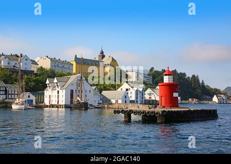 Historische Gebäude, Pier und traditionelle Fischerboote entlang der Uferpromenade des Hafens. Leuchtturm im Vordergrund des getty, Alesund, Norwegen Stockfoto