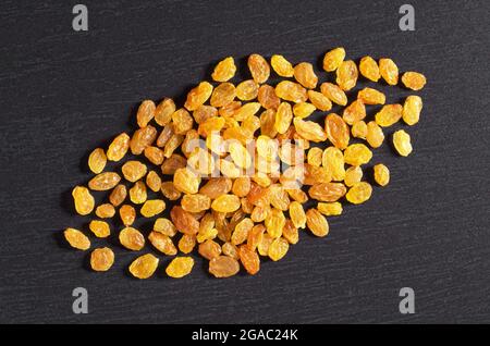 Haufen Rosinen auf schwarzem Stein Hintergrund, Draufsicht Stockfoto