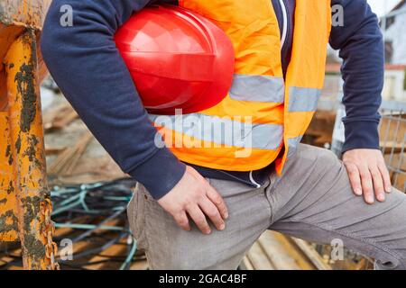 Bauarbeiter oder Handwerker mit rotem Hut und Sicherheitsweste in orange auf einer Baustelle Stockfoto