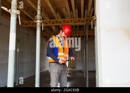 Handwerker oder Bauvermesser mit Tablet-Computer in der Schale einer Baustelle während einer Inspektion Stockfoto