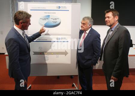 Düsseldorf, Deutschland. Juli 2021. Andreas Müller (l-r), Leiter der operativen Fallanalyse, LKA, erklärt Innenminister Herbert Reul (CDU) eine Informationstafel mit "Cold Case"-Statistiken. Rechts im Bild ist Ingo Wünsch, Direktor des Landeskriminalamtes Nordrhein-Westfalen. „kalte Fälle“ bedeuten ungeklärte Todesfälle. Kredit: David Young/dpa/Alamy Live Nachrichten Stockfoto