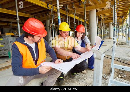 Handwerker-Team und Architekt diskutieren gemeinsam auf der Baustelle im Rohbau Baupläne Stockfoto