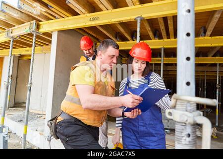 Handwerker und Architekt mit Checkliste bei der Planung der Arbeiten auf der Baustelle im Rohbau Stockfoto