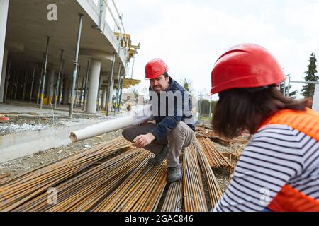 Architekt und Bauarbeiter bei der Qualitätskontrolle von Baustahl auf der Baustelle im Rohbau Stockfoto