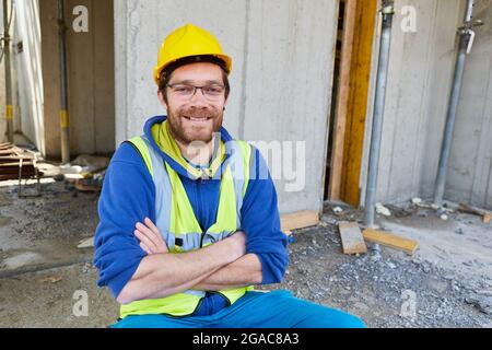 Mann als stolzer Handwerker-Vorarbeiter mit gefalteten Armen auf der Schale einer Baustelle Stockfoto