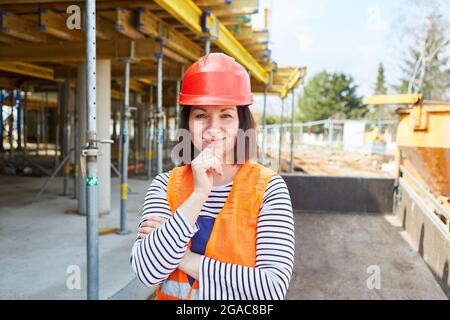 Frau mit rotem Hut auf einer Baustelle als Symbol für die Berufswahl und Frau im Bauberuf Stockfoto