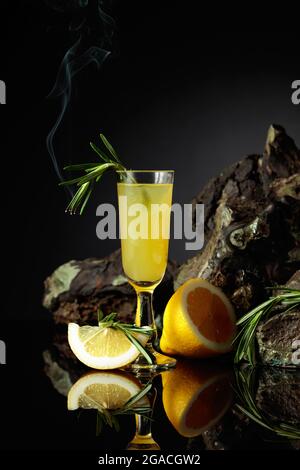 Traditioneller hausgemachter Zitronenlikör Limoncello und frische Zitrusfrüchte auf dem schwarzen reflektierenden Hintergrund. Italienische traditionelle Likör Limoncello mit Zitrone s Stockfoto