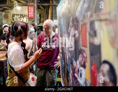 (210730) -- CHONGQING, 30. Juli 2021 (Xinhua) -- Chen Anjian (1. R) spricht mit einem Kunden, der eingeladen wird, sein Ölgemälde im Communications Teahouse im südwestlichen chinesischen Chongqing anzukritzeln, 26. Juli 2021. Chen Anjian, 62, ein Ölgemälde-Lehrer am Sichuan Fine Arts Institute, besucht seit mehr als 20 Jahren das Chongqing Communications Teahouse. Das 1987 gegründete Teehaus Communications ist heute das einzige alte Teehaus in Chongqing, das den ursprünglichen Stil der 1970er und 1980er Jahre beibehalten hat. Es ist eines der wichtigsten kulturellen Wahrzeichen von Chongqing und wird von Tausenden von Tee besucht Stockfoto