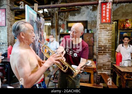 (210730) -- CHONGQING, 30. Juli 2021 (Xinhua) -- Chen Anjian (Front R) spricht mit seinem Modell, der auch einer seiner alten Teetrinker-Freunde ist, während er an einem Ölgemälde im Communications Teahouse im südwestlichen chinesischen Chongqing arbeitete, 26. Juli 2021. Chen Anjian, 62, ein Ölgemälde-Lehrer am Sichuan Fine Arts Institute, besucht seit mehr als 20 Jahren das Chongqing Communications Teahouse. Das 1987 gegründete Teehaus Communications ist heute das einzige alte Teehaus in Chongqing, das den ursprünglichen Stil der 1970er und 1980er Jahre beibehalten hat. Es ist eines der wichtigsten kulturellen Wahrzeichen von Chon Stockfoto