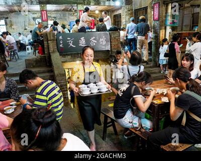 (210730) -- CHONGQING, 30. Juli 2021 (Xinhua) -- EINE Kellnerin betreut die Kunden im Communications Teahouse im südwestlichen chinesischen Chongqing, 26. Juli 2021. Chen Anjian, 62, ein Ölgemälde-Lehrer am Sichuan Fine Arts Institute, besucht seit mehr als 20 Jahren das Chongqing Communications Teahouse. Das 1987 gegründete Teehaus Communications ist heute das einzige alte Teehaus in Chongqing, das den ursprünglichen Stil der 1970er und 1980er Jahre beibehalten hat. Es ist eines der wichtigsten kulturellen Wahrzeichen von Chongqing und wird jeden Tag von tausenden Teeliebhabern besucht. „das Teahouse für Kommunikation ist Stockfoto