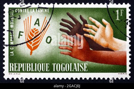 TOGO - UM 1963: Eine in Togo gedruckte Briefmarke zeigt Hände, die nach dem FAO-Emblem greifen, FAO Freedom from Hunger Campaign, um 1963 Stockfoto