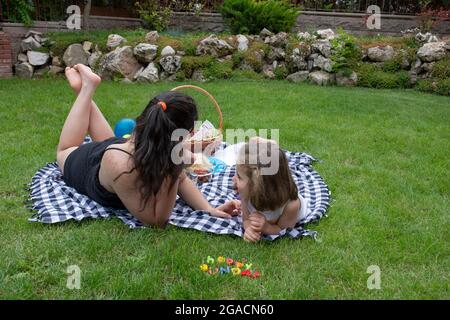 Zwei Schwestern liegen auf dem Gras und unterhalten sich Stockfoto
