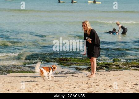 Hund läuft zur Frau am Strand. St Ives, Cornwall, Großbritannien. Stockfoto