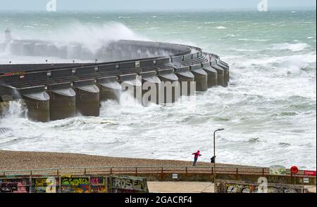 Brighton UK 30. Juli 2021 - Spaziergänger am Strand an der Westwand der Brighton Marina, während Sturm Evert durch das Land fegt und Windgeschwindigkeiten von bis zu 60 km/h in einigen Gegenden prognostiziert werden : Credit Simon Dack / Alamy Live News Stockfoto