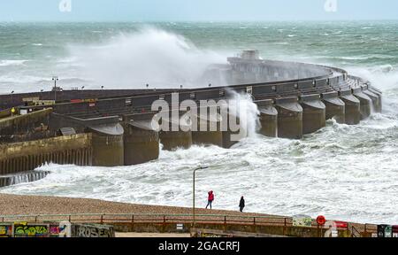 Brighton UK 30. Juli 2021 - Spaziergänger am Strand an der Westwand der Brighton Marina, während Sturm Evert durch das Land fegt und Windgeschwindigkeiten von bis zu 60 km/h in einigen Gegenden prognostiziert werden : Credit Simon Dack / Alamy Live News Stockfoto