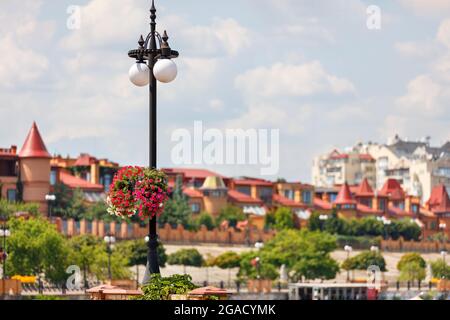 Eine Straßensäule mit zwei Kugelpfeilern ist an einem sonnigen Sommertag mit einer schönen, blühenden Petunie geschmückt. Stockfoto