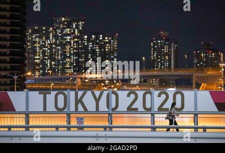 30. Juli 2021, Japan, Tokio: Eine Frau geht nachts am Zug „Tokyo 2020“ vorbei. Die Olympischen Spiele 2020 in Tokio finden von 23.07.2021 bis 08.08.2021 statt. Foto: Jan Woitas/dpa-Zentralbild/dpa Stockfoto