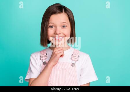 Foto von nachdenklichen jungen glücklichen kleinen Mädchen halten Hand kitzelig gesinnt isoliert auf pastellfarbenem blauem Hintergrund Stockfoto