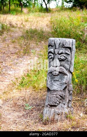 Hölzernes Idol des slawischen gottes durch einen Pfad im Wald Stockfoto