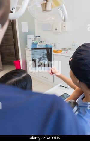 Junge Zahnärztin, die die Röntgenaufnahme eines Patienten überprüft. Stockfoto