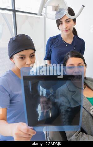 Junge Zahnärztin, die die Röntgenaufnahme eines Patienten überprüft. Stockfoto
